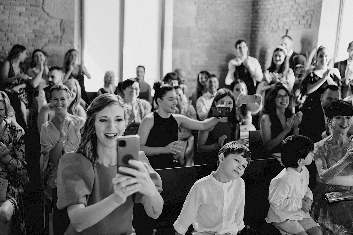 invitados sonriendo y haciendo fotografias a alos novios en la ceremonia