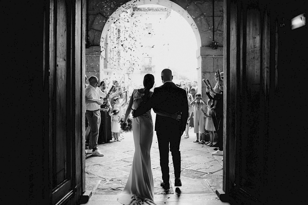 novios saliendo de la ceremonia por un arco de piedra mientras amigos y familia tiran confeti en Andoain