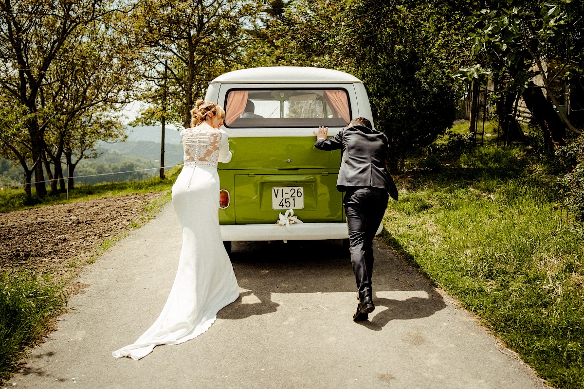 Los novios empujando su furgoneta en el paseo fotográfico de su boda en Orio